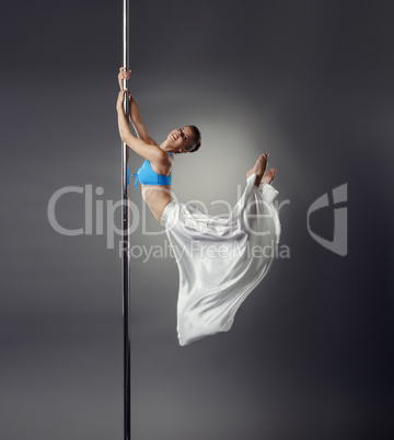 Pretty dancer bent elegantly while dancing on pole