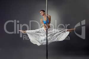 Flexible pretty girl dancing on pole in studio