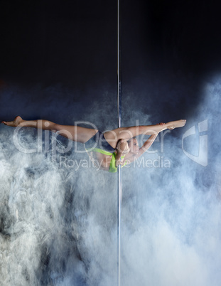 Flexible pole dancer performs acrobatic pas