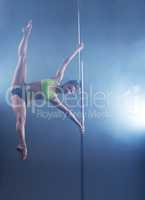 Pole dance. Strong girl froze in stretching pose