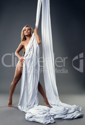Sexy blonde posing nude hiding behind aerial silks
