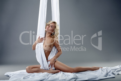 Hot blonde posing among silks hanging from ceiling