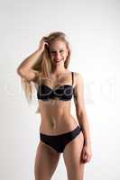 Smiling athletic model posing in black lingerie