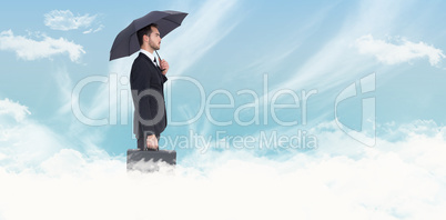 Composite image of businessman under umbrella while holding a br