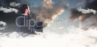 Composite image of businessman in suit holding laptop