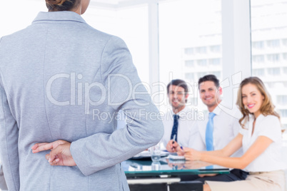 Composite image of businesswoman with fingers crossed behind her