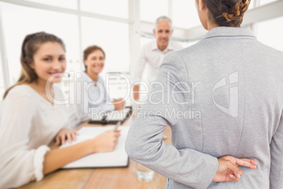 Composite image of businesswoman with fingers crossed behind her