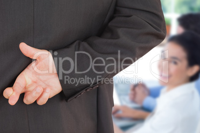 Composite image of businessman with fingers crossed
