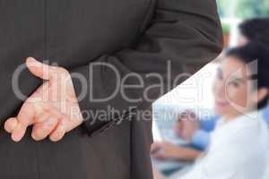 Composite image of businessman with fingers crossed