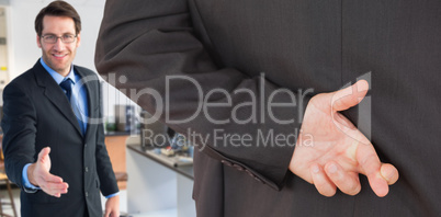 Composite image of businessman with fingers crossed