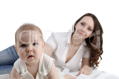 Cute baby posing at camera and her mom on backdrop