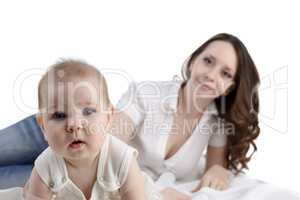 Cute baby posing at camera and her mom on backdrop