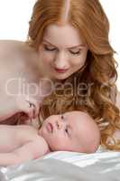 Pretty red-haired mother takes care of her baby