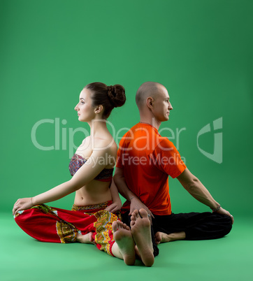 Paired yoga training in studio, on green backdrop