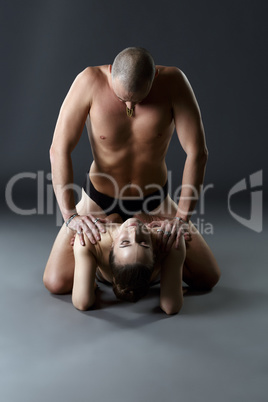 Nude paired yoga. Man rests on shoulders of woman