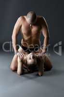 Nude paired yoga. Man rests on shoulders of woman