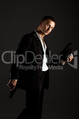 Sexy man posing as mafiosi, on gray background