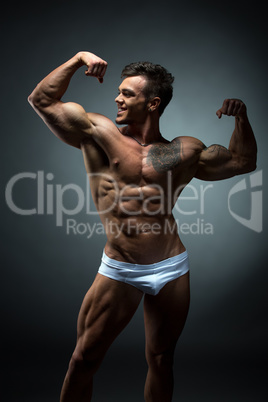 Image of smiling bodybuilder admires his biceps