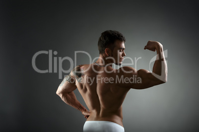 Rear view of tattooed bodybuilder showing biceps