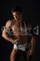 Muscular man posing with chain at camera