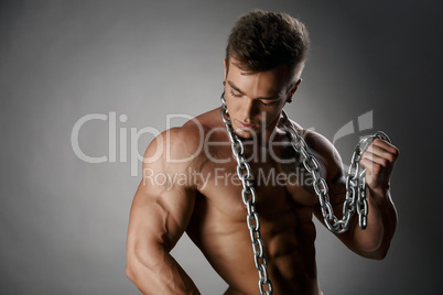 Portrait of tanned bodybuilder posing with chain