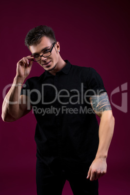 Stylish young man with glasses, on pink backdrop