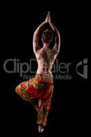 Rear view of slender topless woman practicing yoga