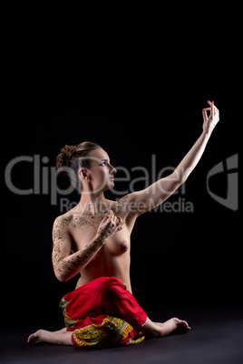 Attractive topless woman practicing yoga in studio