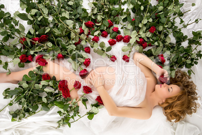 Image of pregnant woman posing in bed with roses