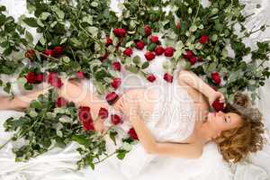 Image of pregnant woman posing in bed with roses