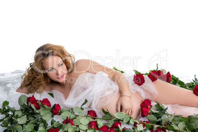 Red-haired pregnant woman posing among roses