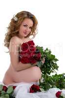 Nude pregnant woman posing with rose bouquet