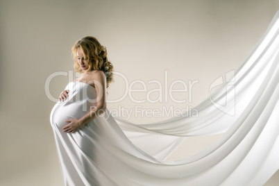 Pregnant woman in elegant dress with flying plume