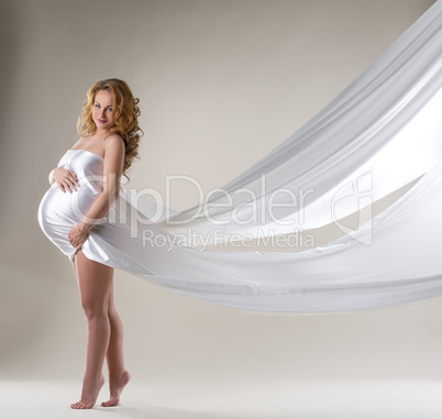 Charming pregnant woman posing with flying dress
