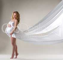 Charming pregnant woman posing with flying dress