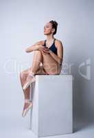 Beddable ballerina sitting on cube in studio