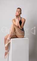 Sensual ballet dancer posing sitting on cube