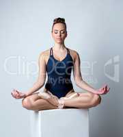 Image of beautiful ballerina meditates on cube