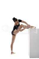 Ballerina put her foot on cube and tying pointes