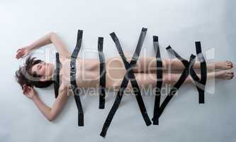 BDSM concept. Nude woman with black adhesive tape