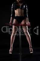 BDSM. Pole dancer with whip in her hands