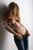 Curly-haired busty blonde posing topless in jeans