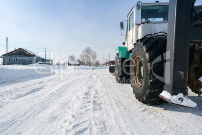 Tractor rides through village in winter