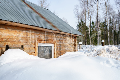 Log house covered with snow in forest