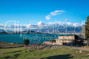 Image of countryside near sea. Dog guarding barn