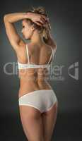 Rear view of slim model posing in white lingerie