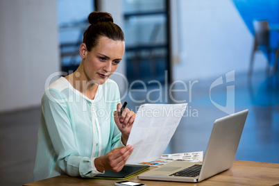 Woman looking a chart with laptop and graphics tablet on desk