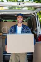 Portrait of smart delivery man carrying cardboard box