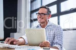Man working on computer and holding digital tablet