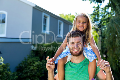 Father carrying daughter on shoulders in yard